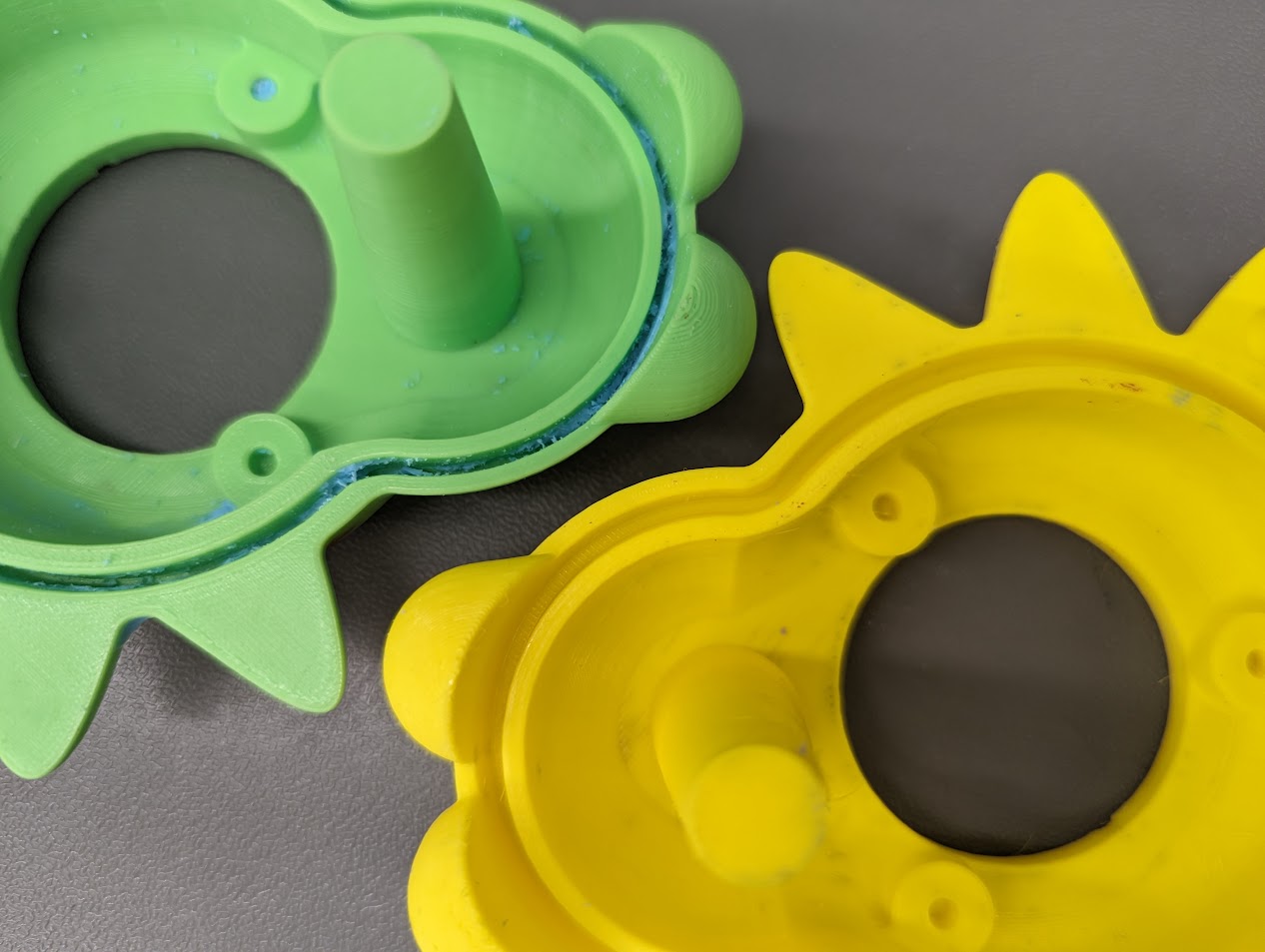 Two iterations of 3d printed mold positives for silicone casting. One with a narrow groove with silicone stuck in it, and the other with a wider groove that releases easily