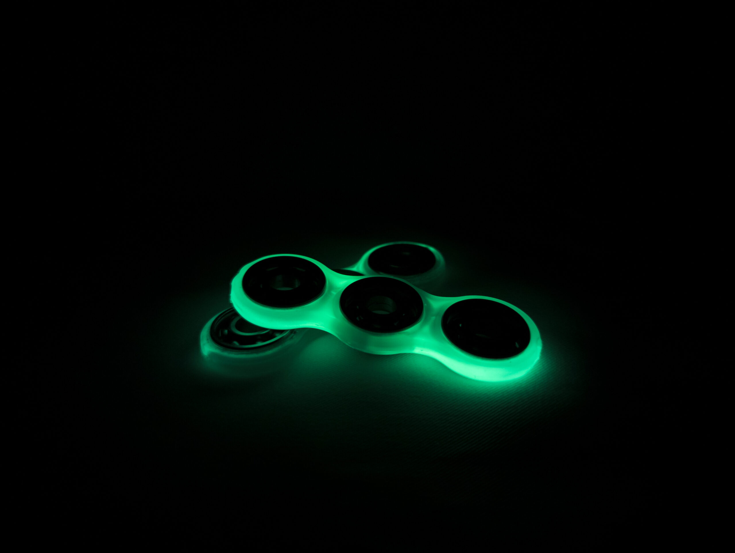 Two overlapping fidget spinners glowing in the dark