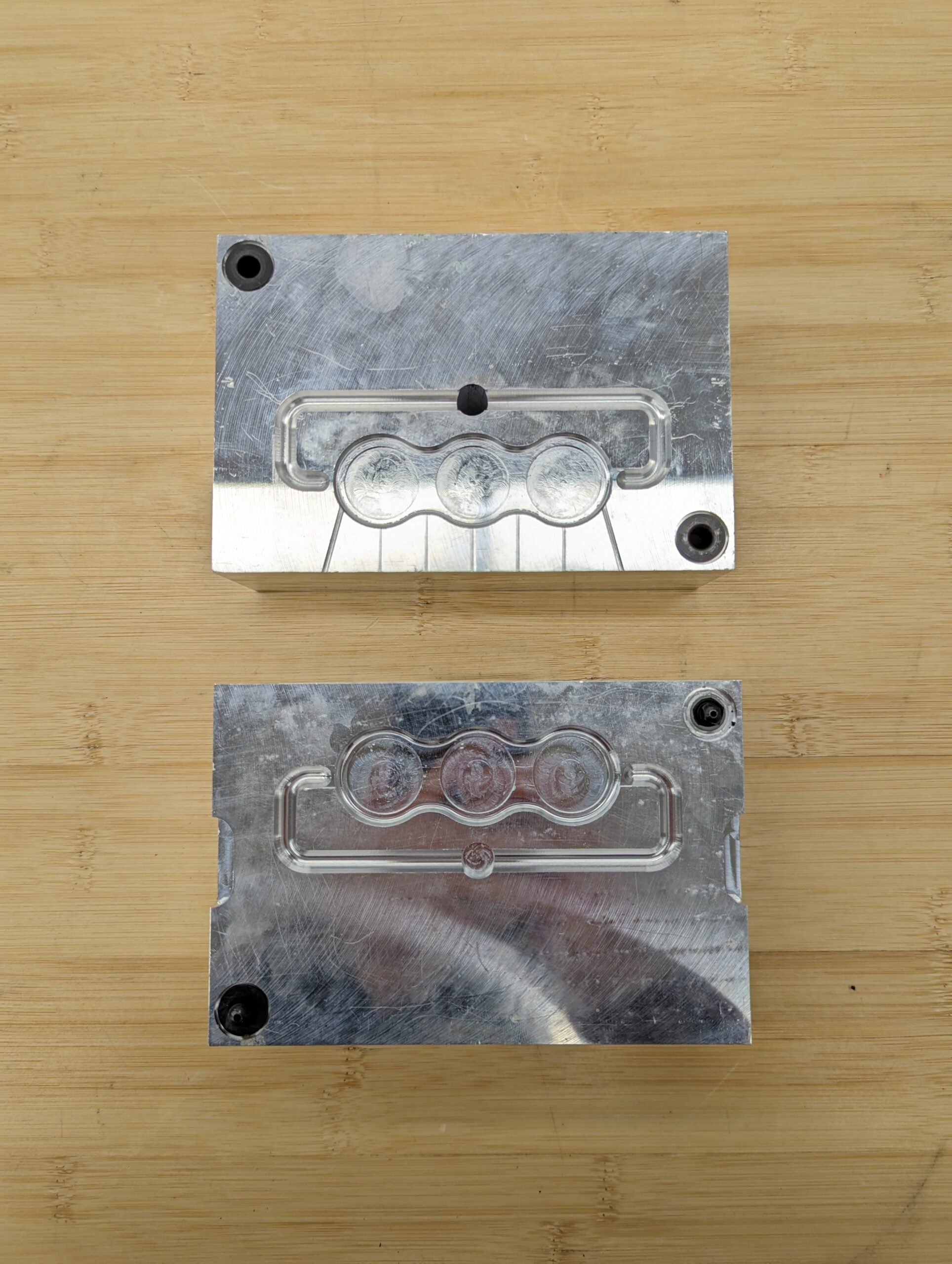 Two aluminum blocks with the negative for injection-molding carved into them, forming a mold