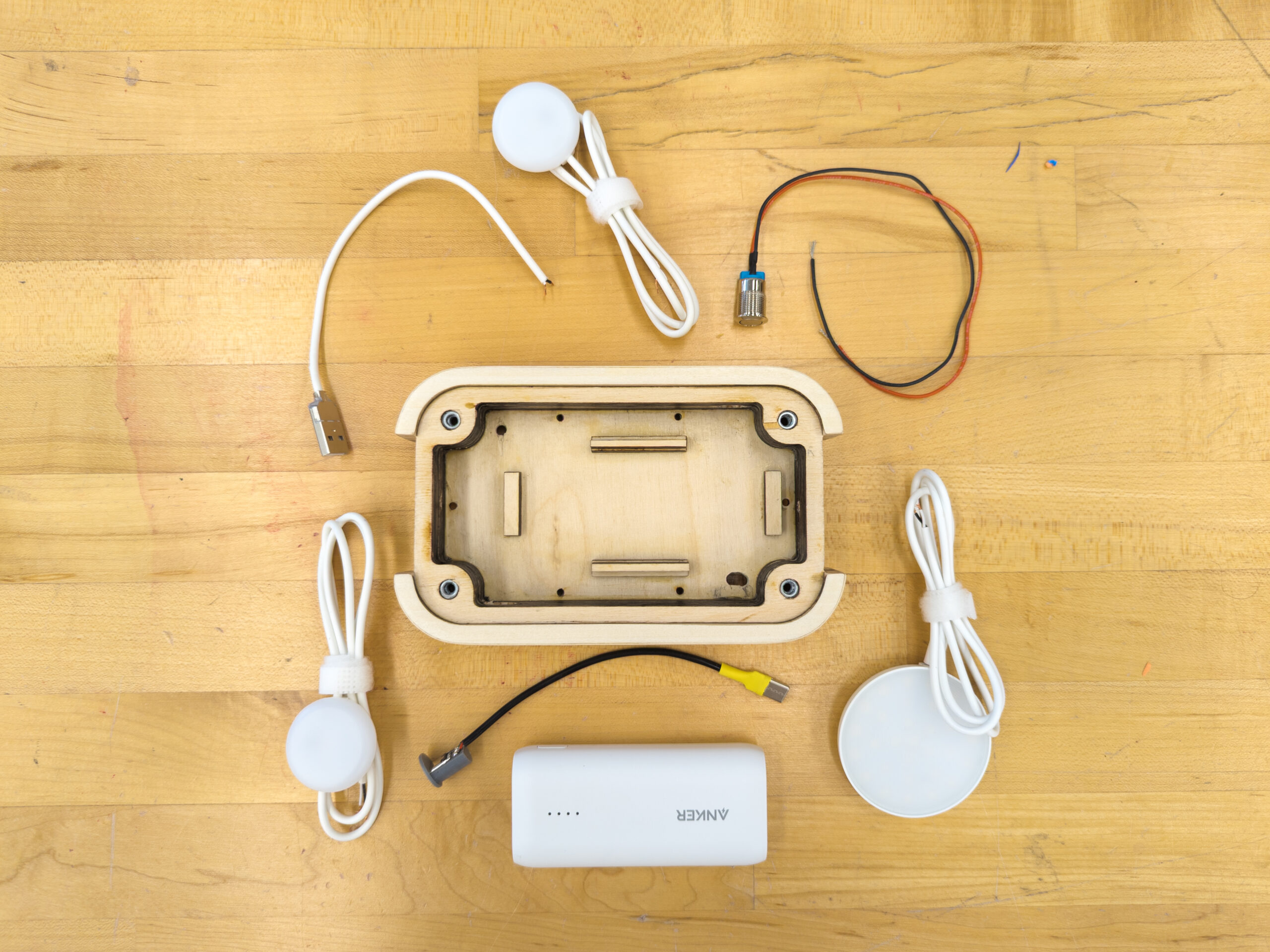 Wood lantern base surrounded by electronic components and wires laid out on a wood tabletop