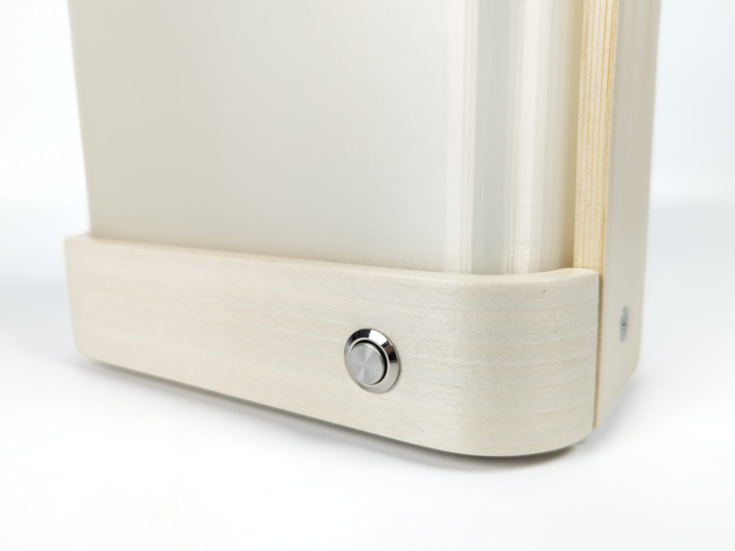 Closeup of wood and plastic lantern against white background with shiny metal push-button shown.