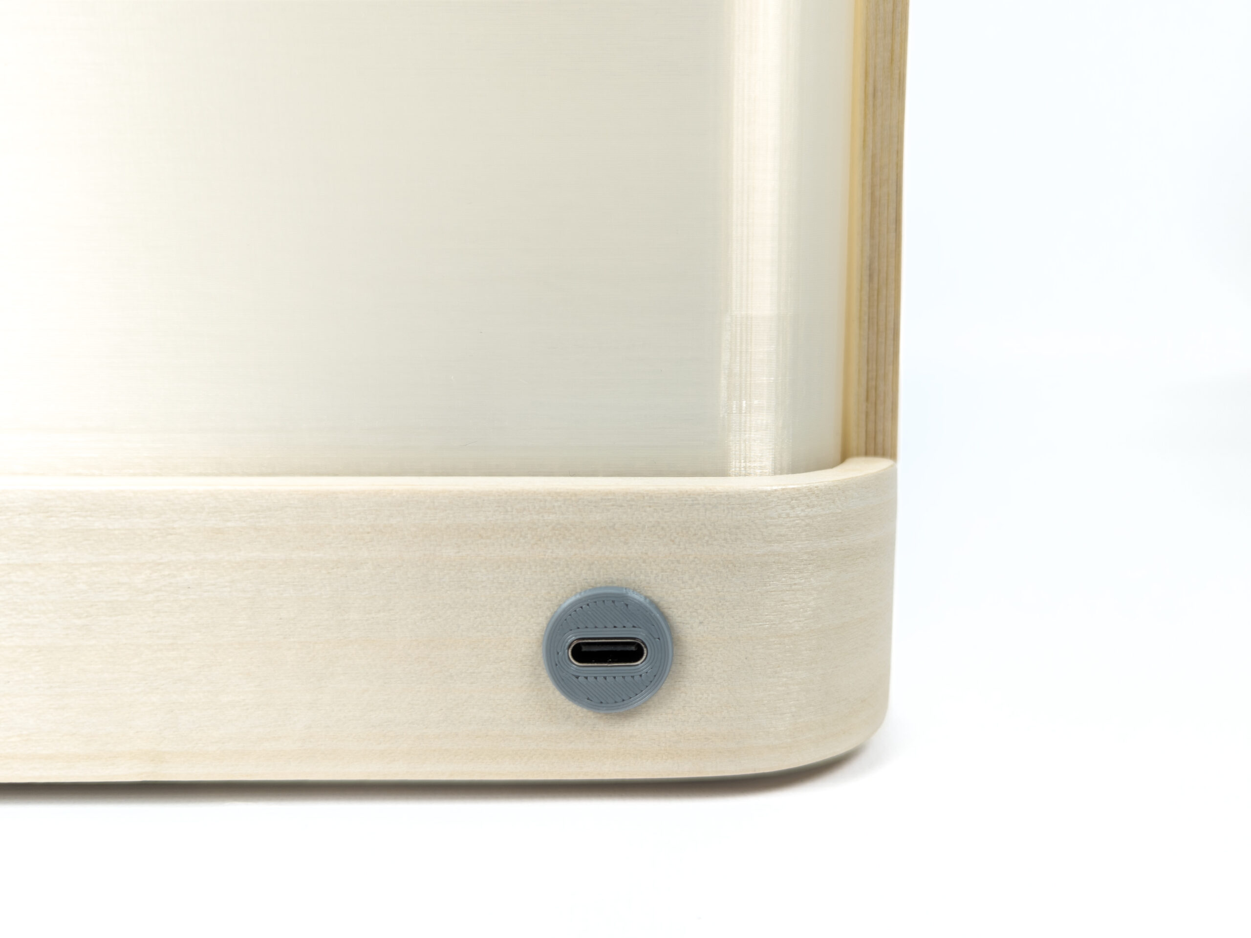 Closeup of 3d-printed enclosure for USB-C port inserted in wood base of lantern. Corner of plastic light diffuser and white background visible.