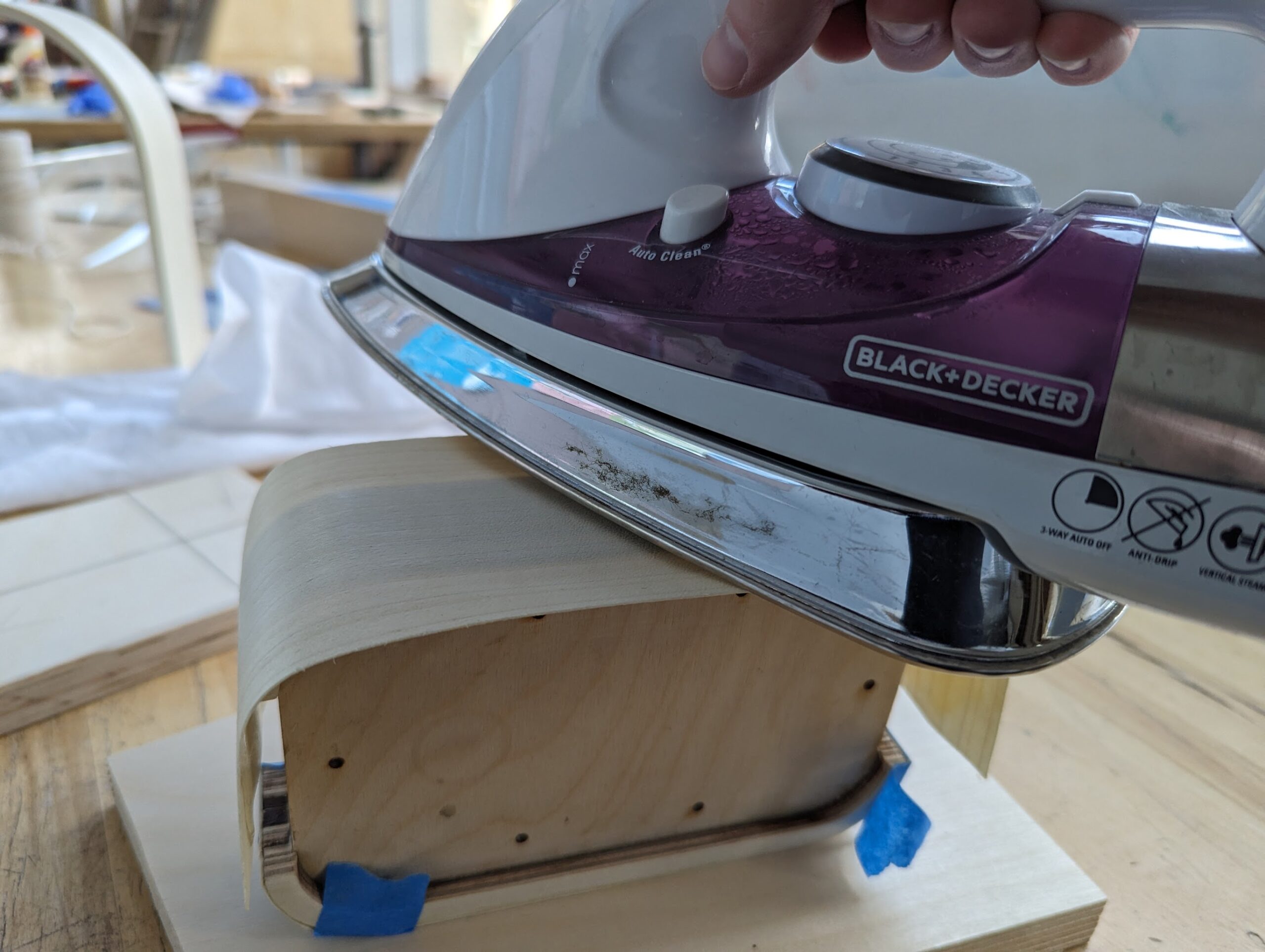 Hand holding a clothes iron against wood veneer to be pressed onto lamp base