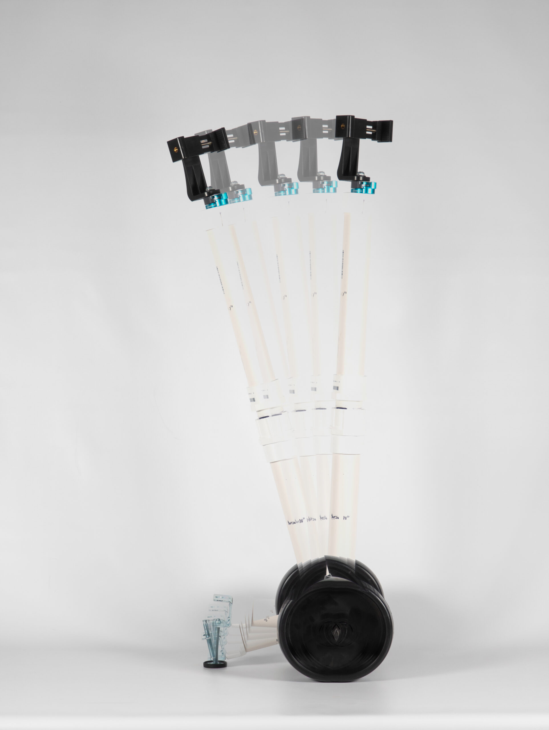 Overlayed images of vertical camera rig made of PVC pipe with large black wheels standing against a white backdrop. Images are stacked to show the rig rotated to different angles.