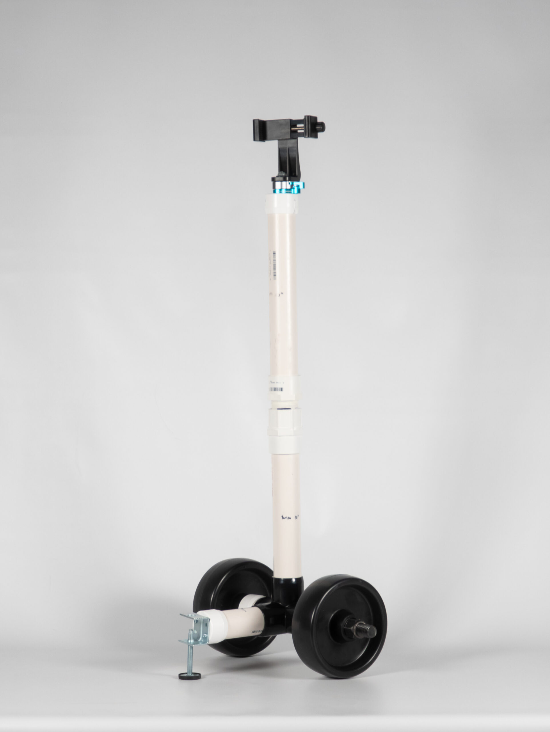 Vertical camera rig made of PVC pipe with large black wheels standing against a white backdrop